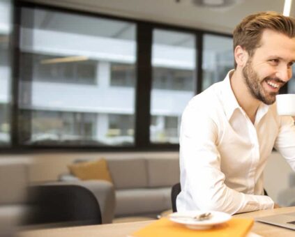 Man smiling at computer with coffee