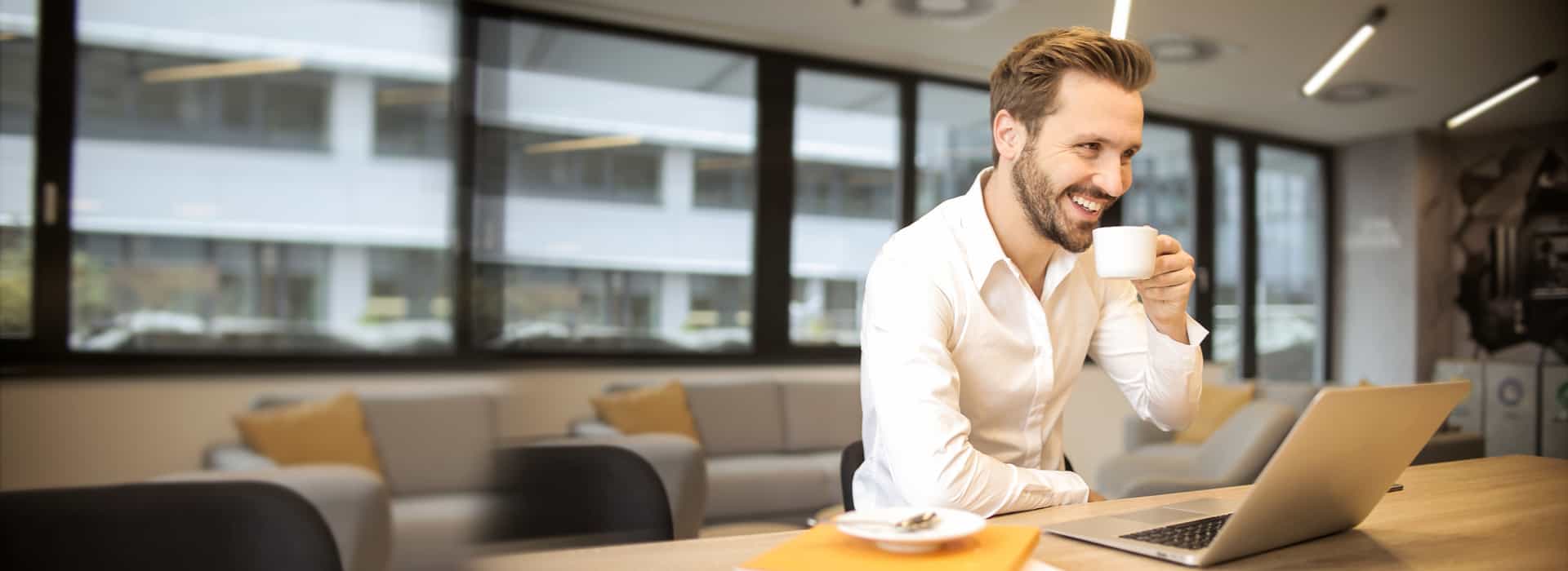 Man smiling at computer with coffee
