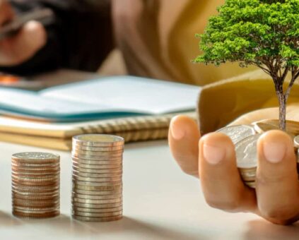 Person doing money calculations with coins, pens and paper