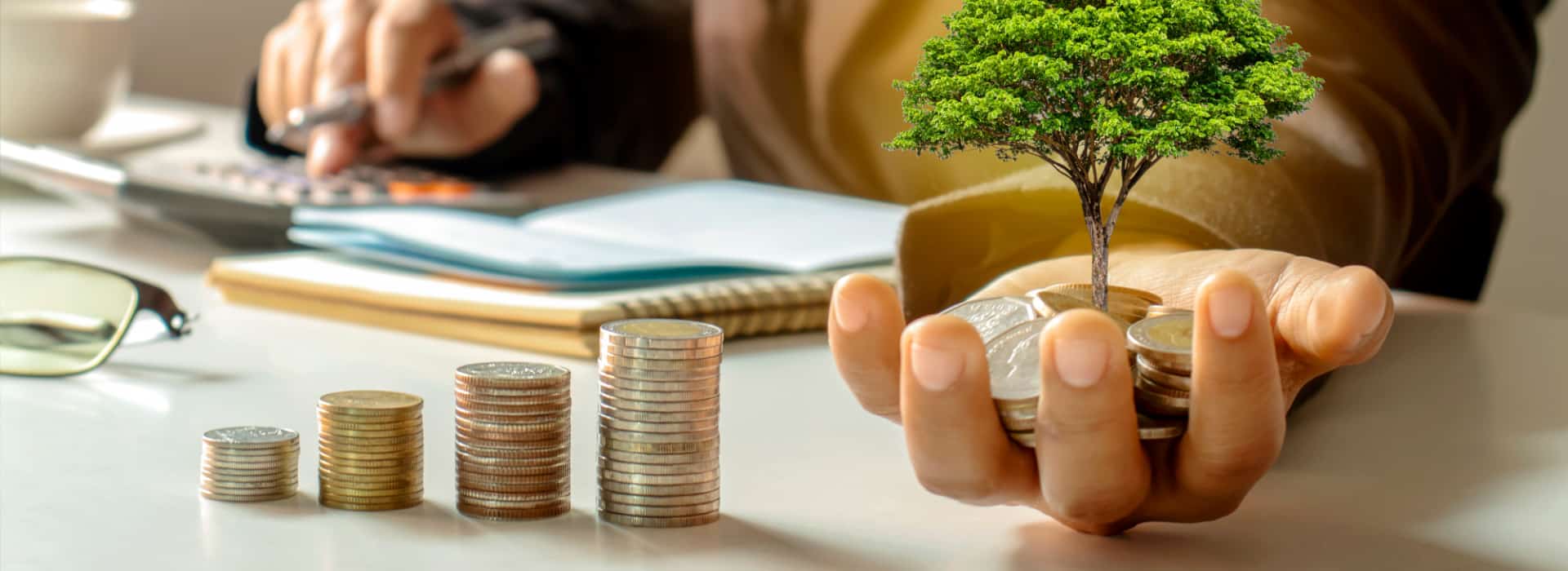 Person doing money calculations with coins, pens and paper