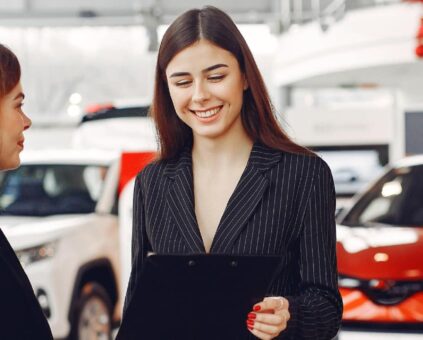 Saleswoman at dealership with happy client