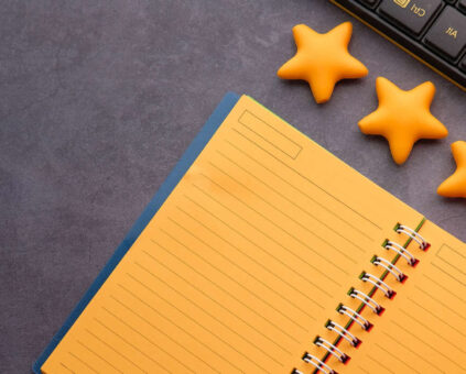 Keyboard placed above notebook with 5 yellow stars