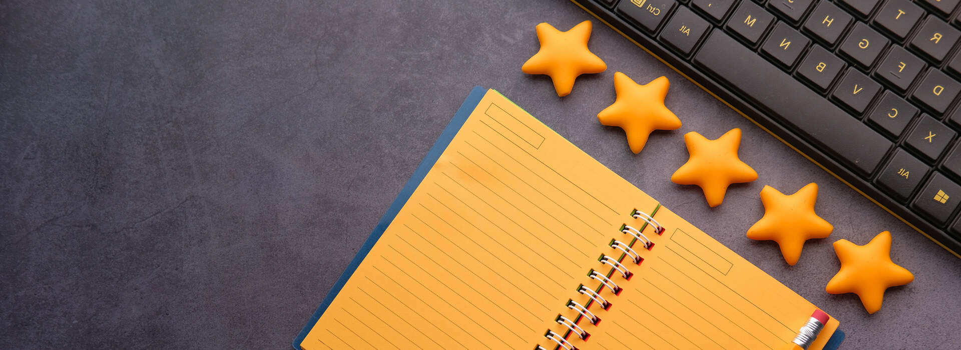 Keyboard placed above notebook with 5 yellow stars