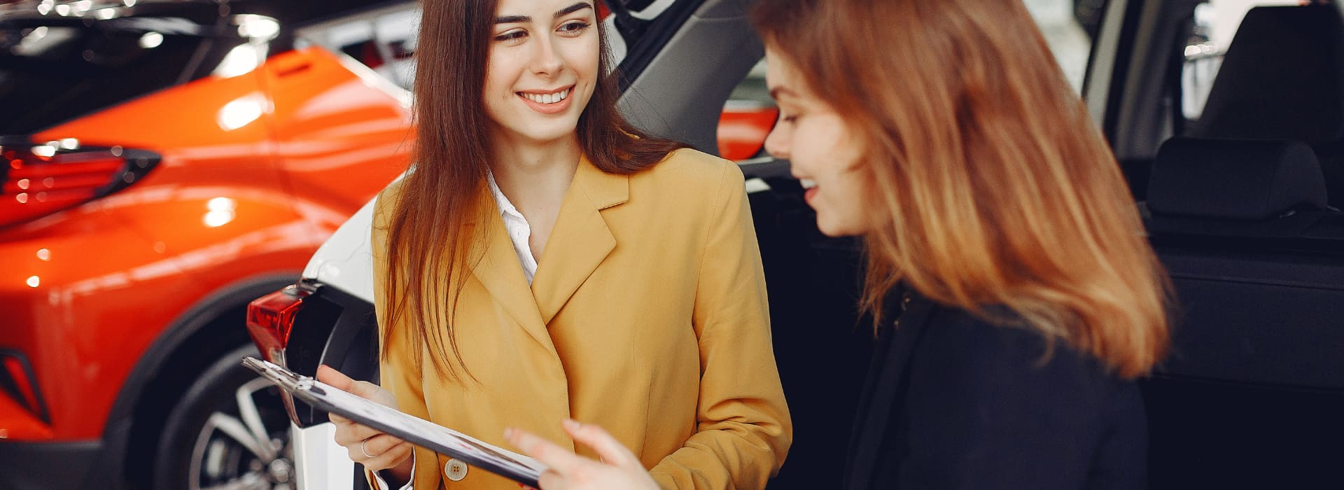 Saleswoman signing up happy customer at dealership