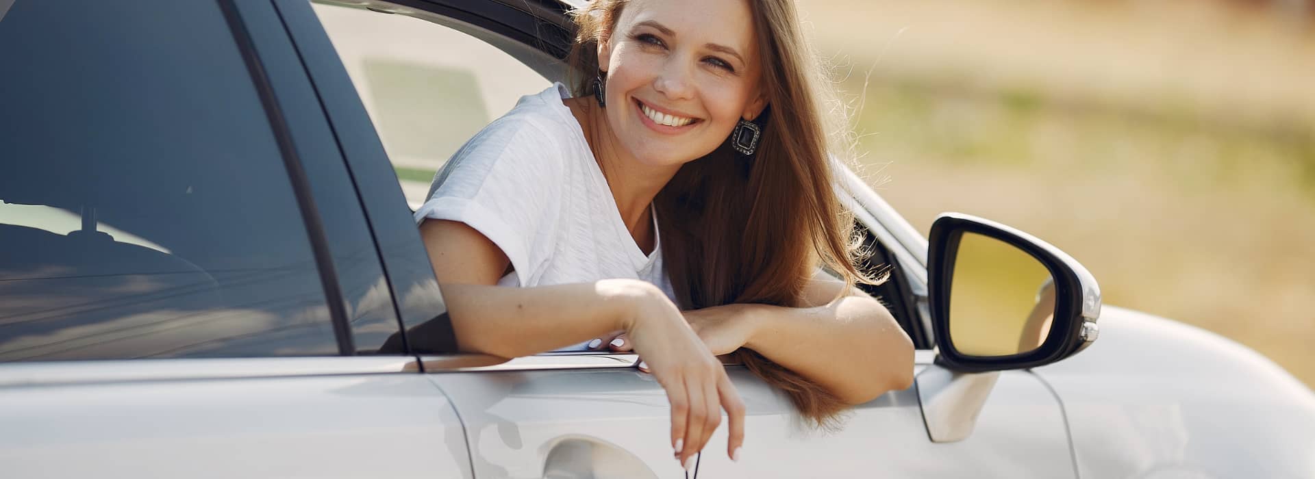 Happy female leaning out of new car