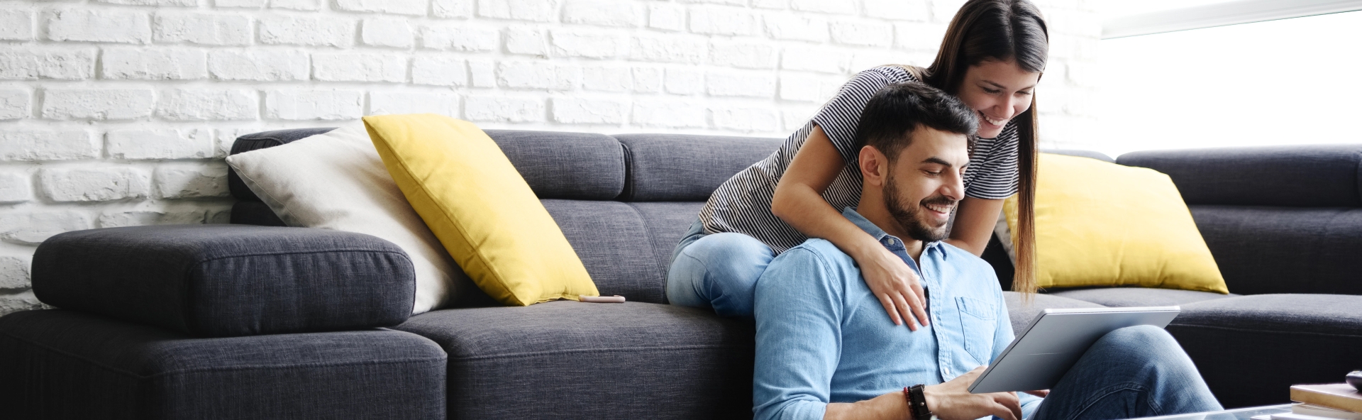 couple smiling on couch looking at laptop