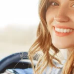 Young female smiling and driving in car
