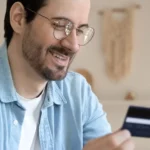Man smiling and making purchase with credit card on phone