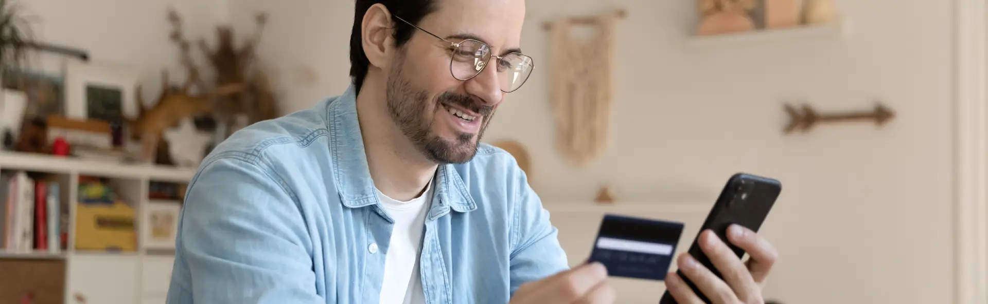 Man smiling and making purchase with credit card on phone