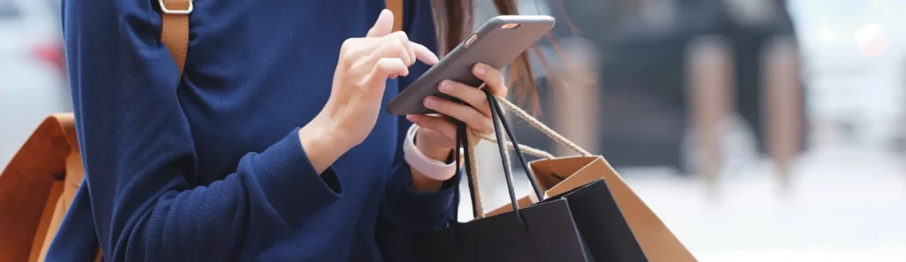 Lady walking on mobile with shopping bags in hand