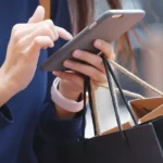 Lady walking on mobile with shopping bags in hand