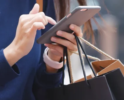 Lady walking on mobile with shopping bags in hand