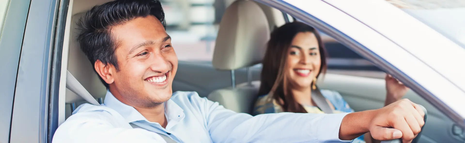 Couple smiling and driving in sedan