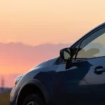 Couple admiring sunset next to new car