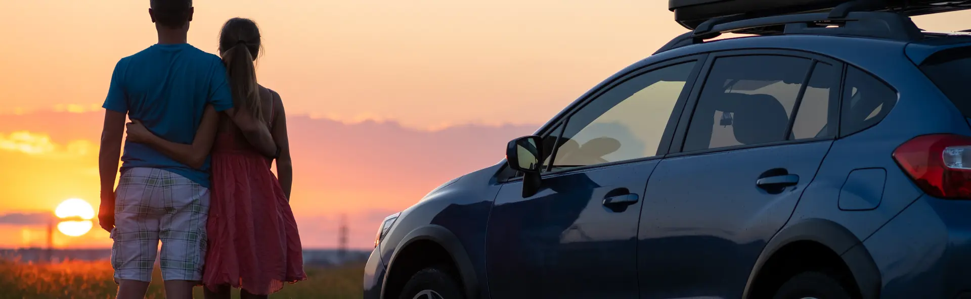 Couple admiring sunset next to new car