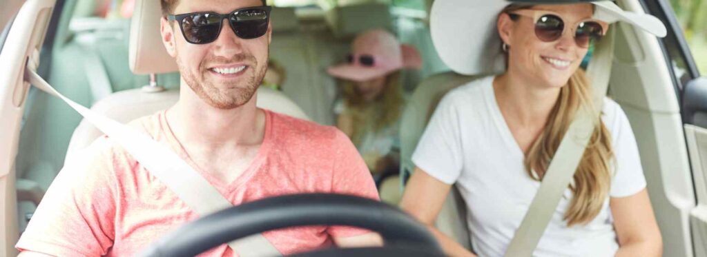 Family driving car and smiling.