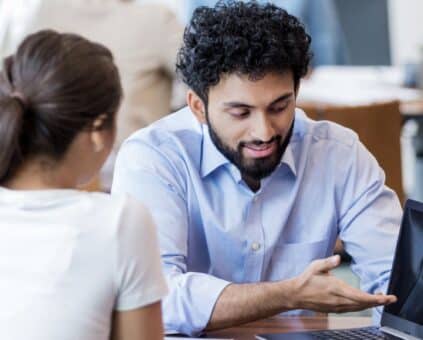 Lending specialist consulting with couple using laptop, discussing secured vs unsecured personal loan options and financial solutions