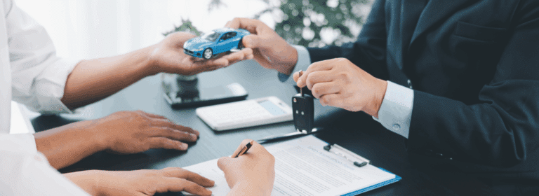 Buyer signing paperwork while a dealer presents car keys, representing the process of securing a bad credit car loan.