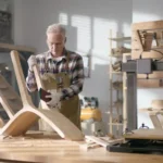 New buisiness owner thinking about getting a loan without financial documents to expand their business while sanding a chair in their workshop.