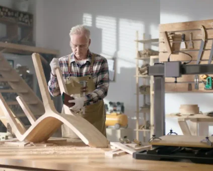 New buisiness owner thinking about getting a loan without financial documents to expand their business while sanding a chair in their workshop.